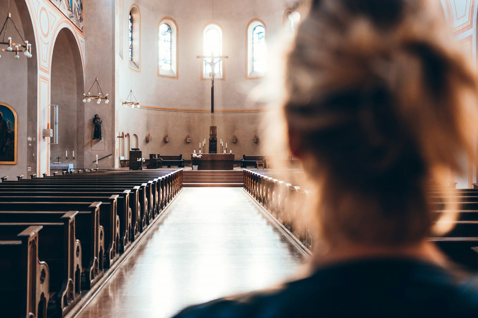 Eine Frau betritt den lichtdurchfluteten Kirchenraum