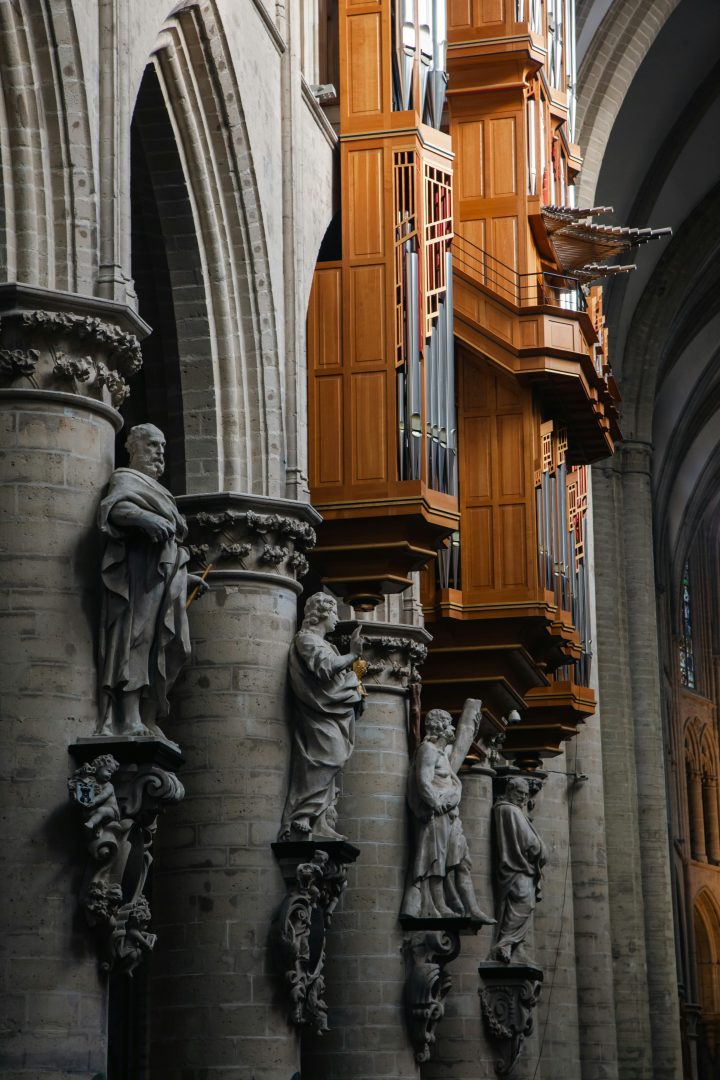 Eine Schwalbennestorgel vom Sonnenlicht erhellt umgeben von dunklen Apostelfiguren