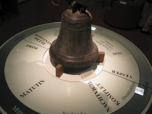 Glocke steht auf einer runden Zeittafel die die Gebetszeiten anzeigt