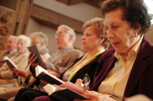 Ältere Menschen singen im Gottesdienst aus dem Gotteslob