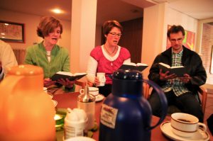 Glaeubige singen beim Gemeindekaffee ein Lied aus dem Gotteslob