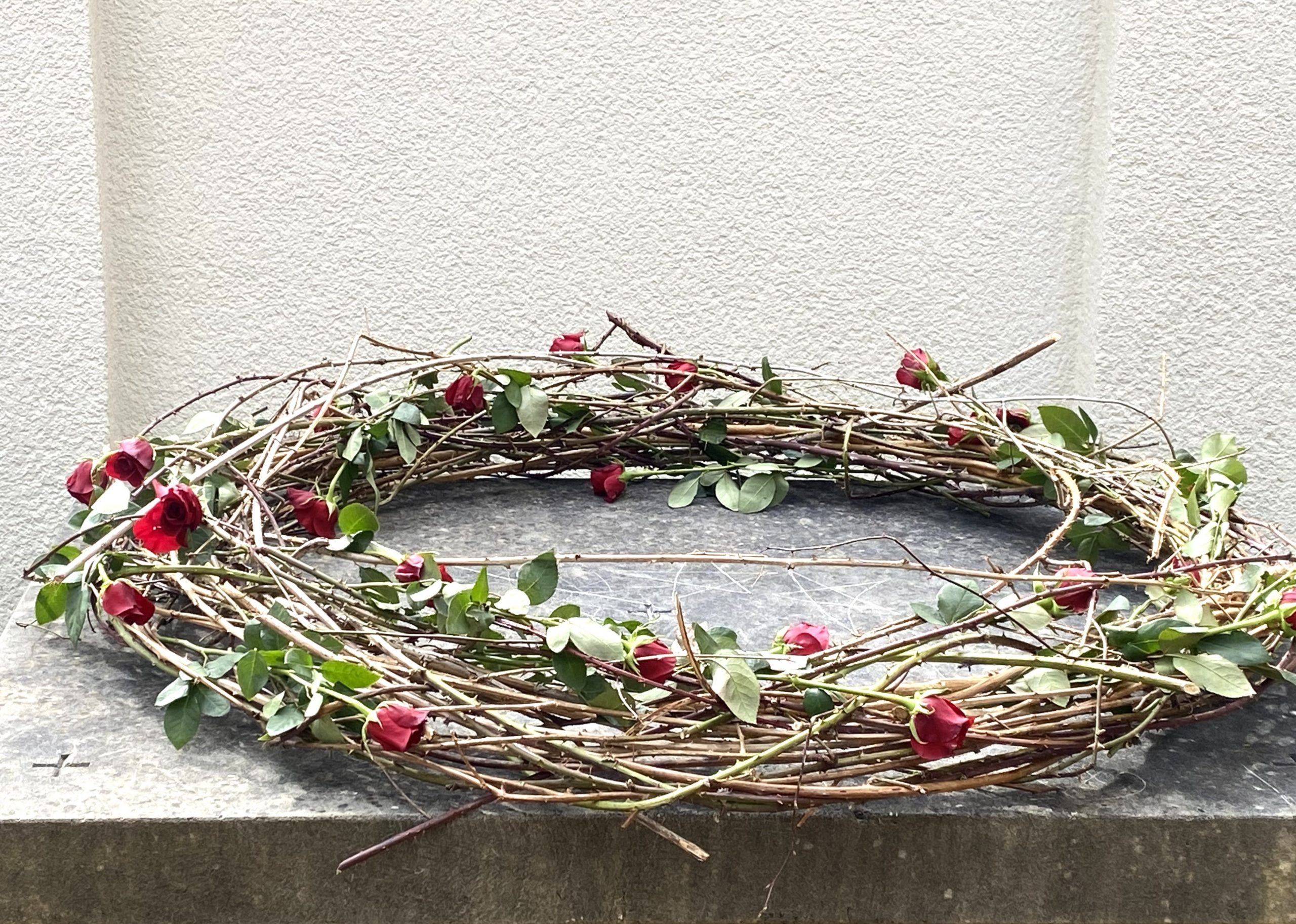 Dornenkrone mit roten Rosen auf einem steinernen Altar