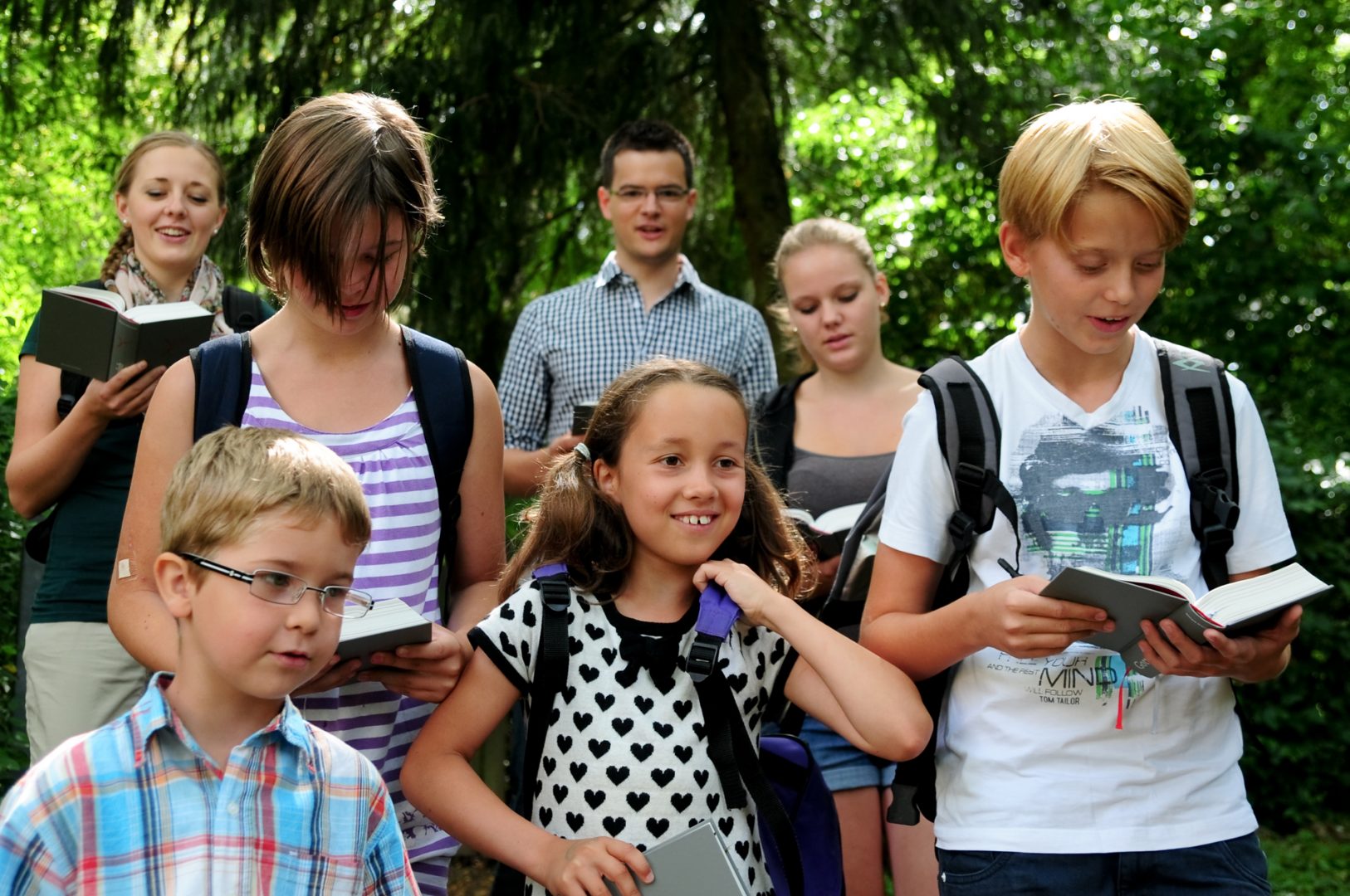 Kinder und Jugendliche beten bei einer Wallfahrt in der Natur aus dem Gotteslob