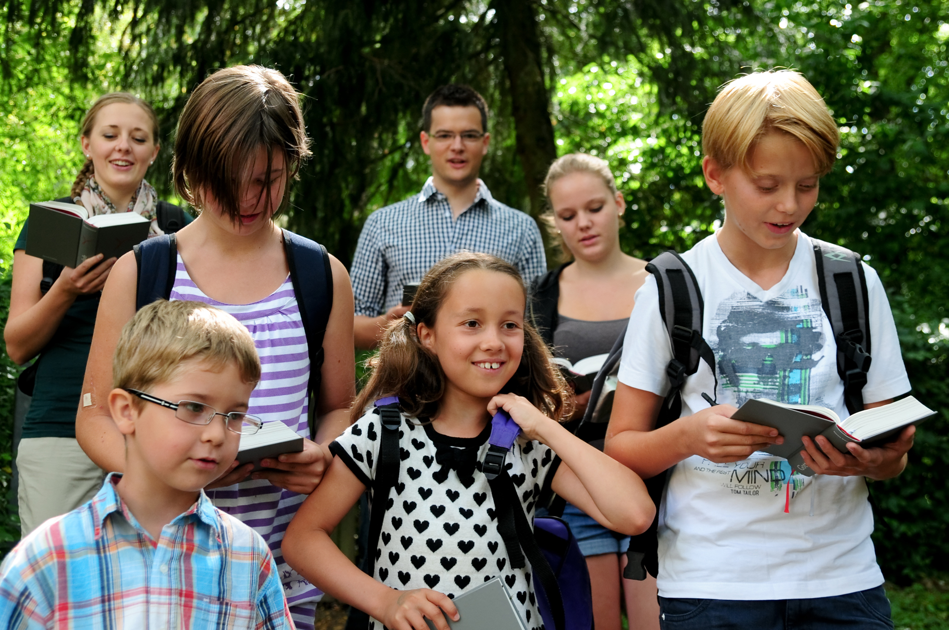 Kinder und Jugendliche beten bei einer Wallfahrt in der Natur aus dem Gotteslob