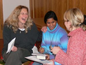 Drei Frauen siten freudig zusammen und bereiten einen Gottesdienst vor