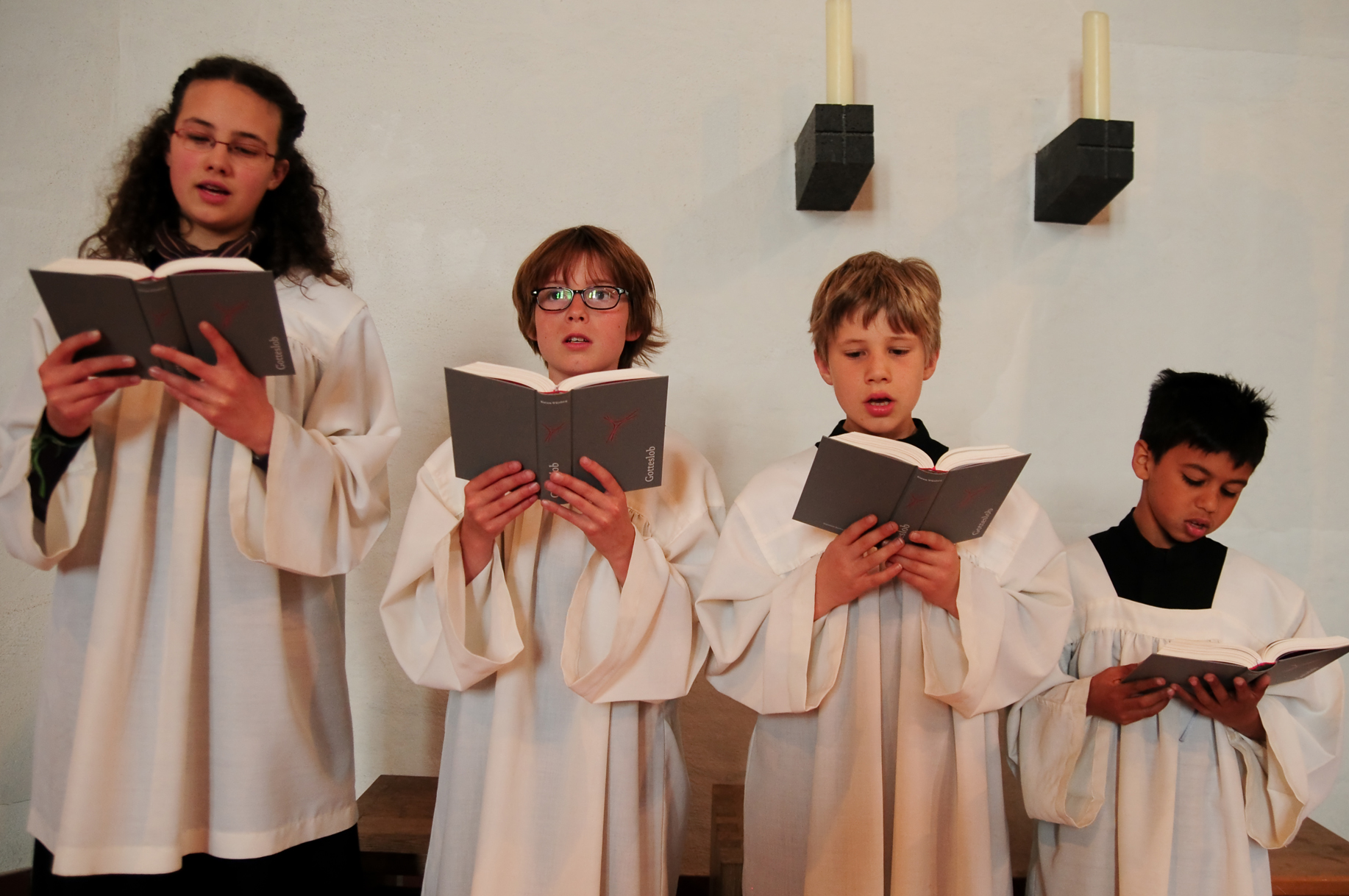 Vier Ministranten singen aus dem Gotteslob