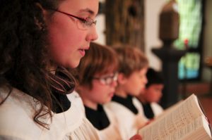 Vier Ministranten singen aus dem Gotteslob