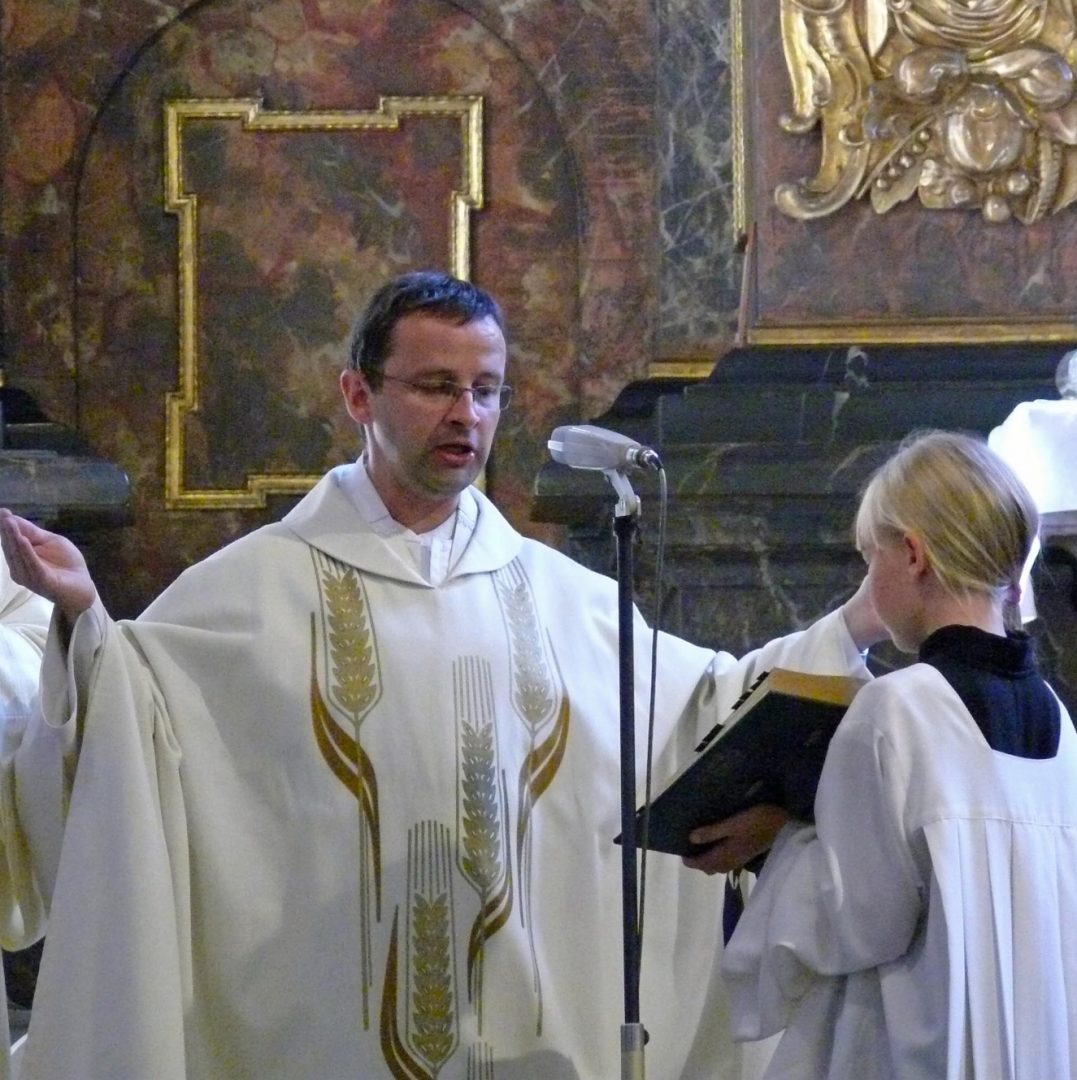 Ein Priester breitet die Haende zur Orantenhaltung aus und betet das Tagesgebet vor