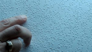 Finger ertastet Brailleschrift auf weißem Papier