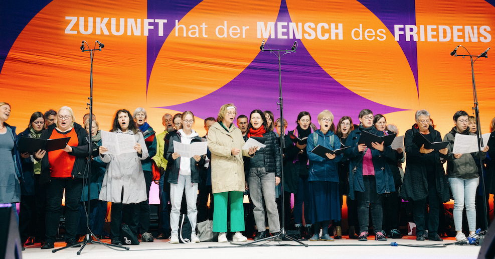 Ein Chor singt auf der Katholikentagsbühne mit dem Hintergrund "Zukunft hat der Mensch des Friedens"